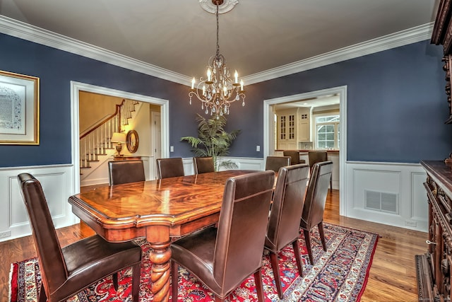 dining space featuring crown molding, light hardwood / wood-style flooring, and an inviting chandelier