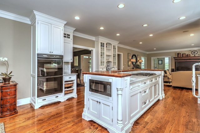 kitchen featuring wood-type flooring, wood counters, stainless steel appliances, white cabinets, and ornamental molding