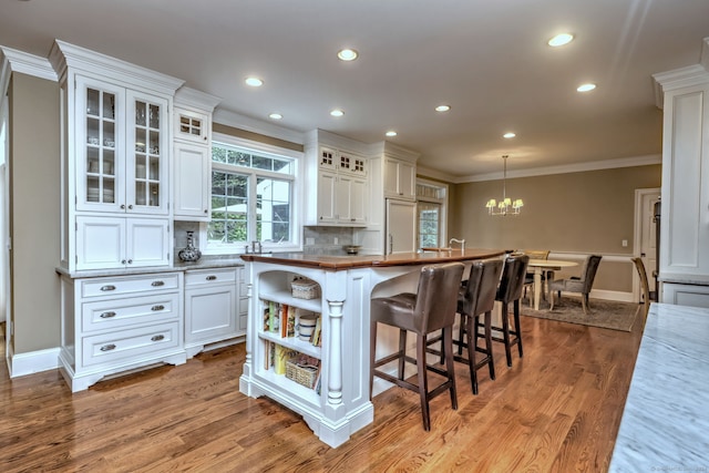 kitchen featuring white cabinetry, light hardwood / wood-style floors, crown molding, and hanging light fixtures