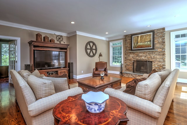 living room with a stone fireplace, ornamental molding, a wealth of natural light, and hardwood / wood-style floors