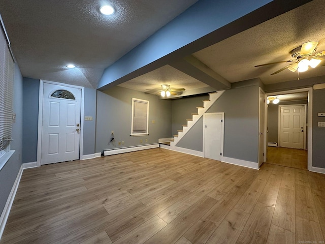 basement with a textured ceiling, light hardwood / wood-style floors, and a baseboard heating unit