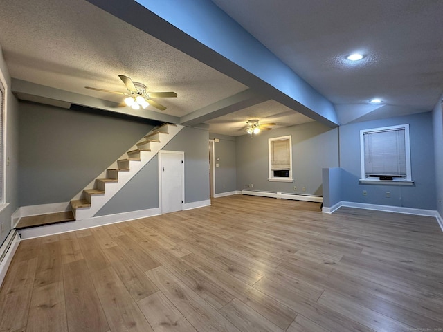 basement featuring a textured ceiling, a baseboard radiator, and light hardwood / wood-style flooring