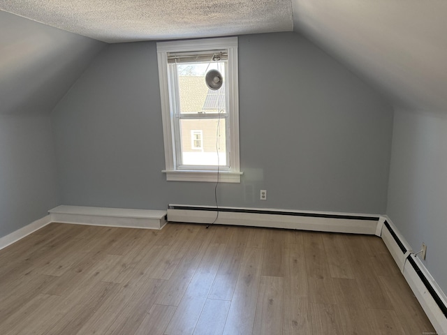 bonus room with baseboard heating, lofted ceiling, light hardwood / wood-style flooring, and a textured ceiling