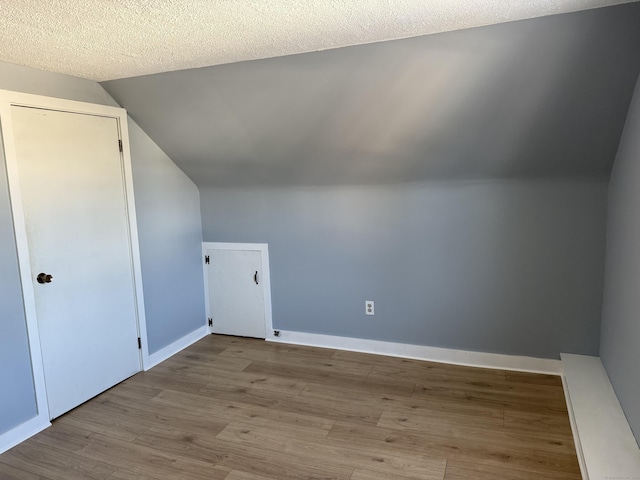 bonus room featuring a textured ceiling, light wood-type flooring, and lofted ceiling