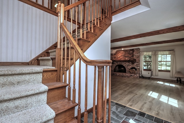 staircase with hardwood / wood-style flooring and a brick fireplace