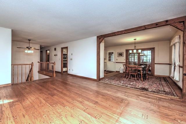 interior space with ceiling fan with notable chandelier, wood-type flooring, and a textured ceiling