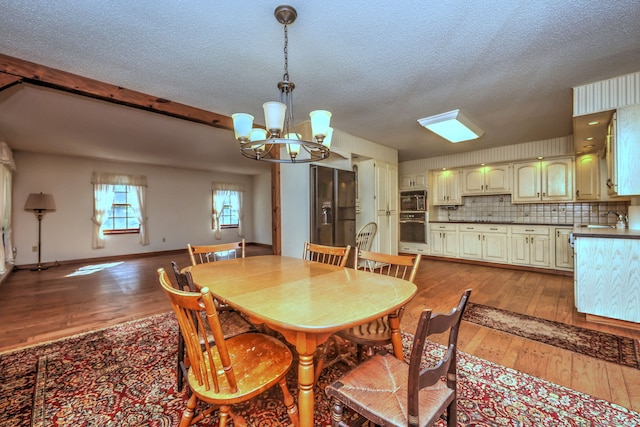 dining area with hardwood / wood-style floors, sink, a textured ceiling, and a chandelier