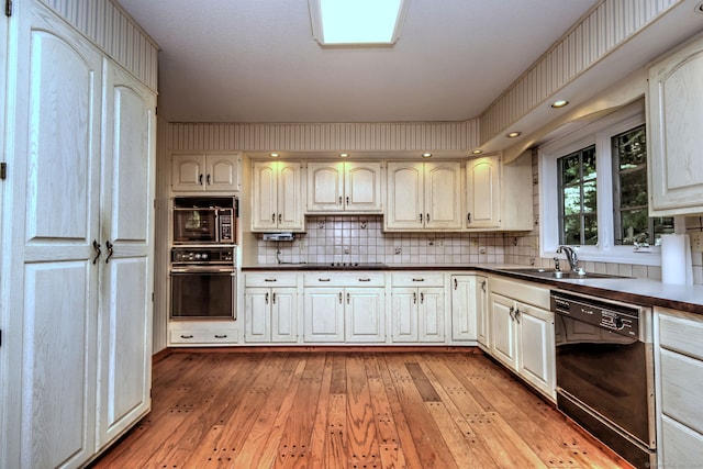 kitchen featuring decorative backsplash, light hardwood / wood-style flooring, black appliances, and sink