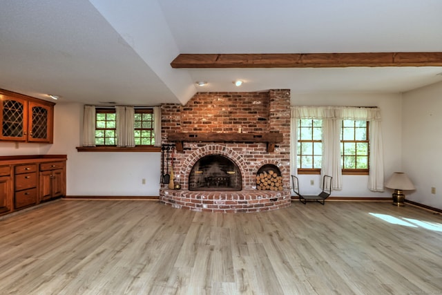 unfurnished living room featuring beamed ceiling, light hardwood / wood-style floors, and a brick fireplace