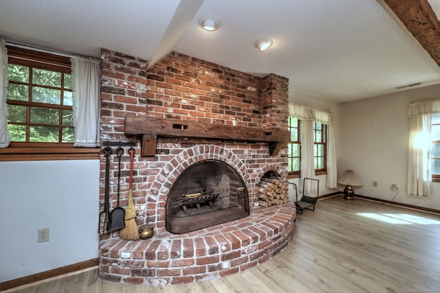 living room with plenty of natural light, a fireplace, wood-type flooring, and a textured ceiling