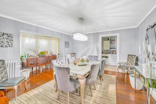 dining space featuring radiator heating unit, crown molding, light hardwood / wood-style flooring, and an inviting chandelier