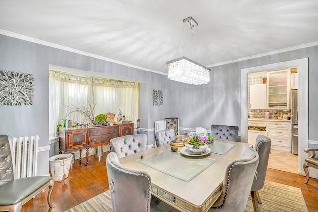 dining space featuring a chandelier, light wood-type flooring, and ornamental molding