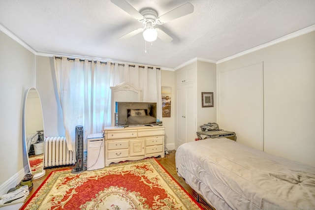 bedroom with hardwood / wood-style flooring, ceiling fan, radiator heating unit, and crown molding