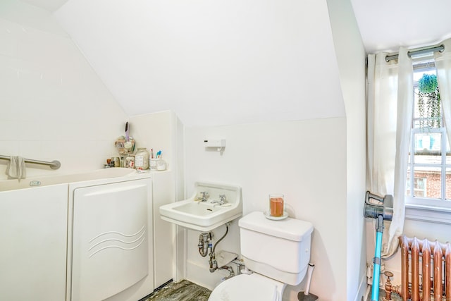 bathroom with radiator, plenty of natural light, vaulted ceiling, and toilet