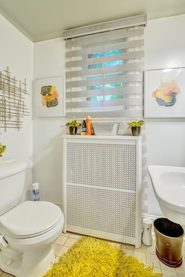 bathroom with toilet, radiator heating unit, and tile patterned flooring