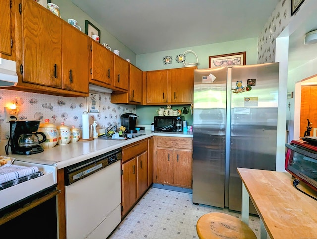 kitchen featuring dishwasher, sink, and stainless steel fridge