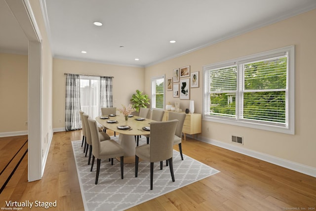 dining room with ornamental molding and light wood-type flooring