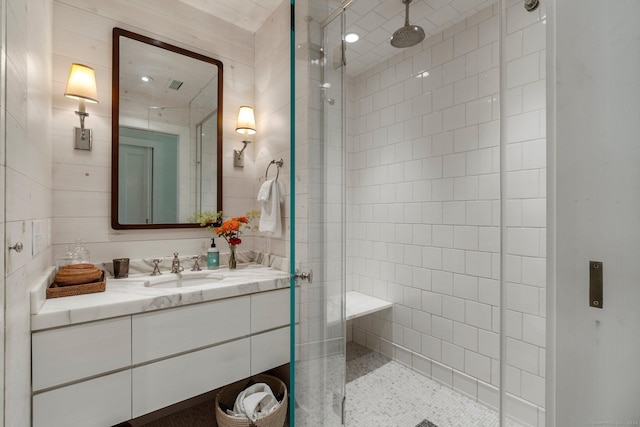 bathroom with vanity, an enclosed shower, and tile walls