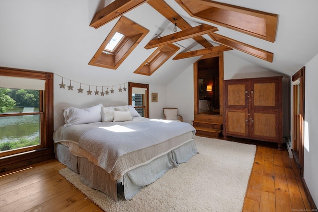 bedroom featuring lofted ceiling with skylight, light hardwood / wood-style floors, and a baseboard radiator