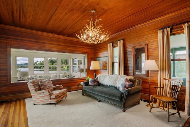 carpeted living room with a chandelier, wooden walls, and wood ceiling