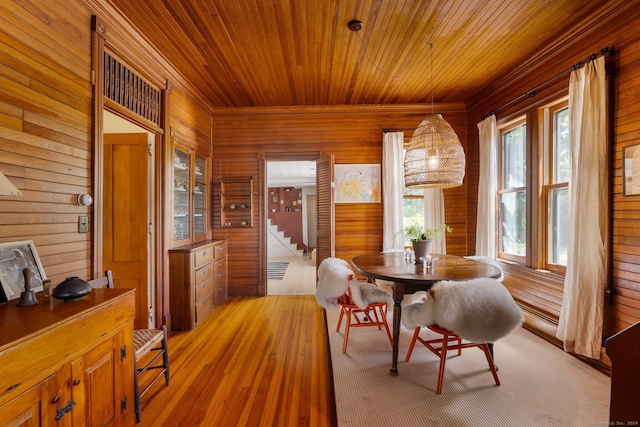 dining area with wood walls, light wood-type flooring, and wood ceiling