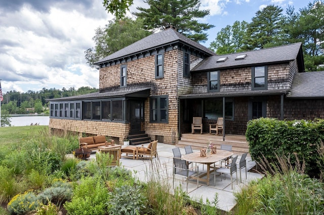 back of house featuring a sunroom, an outdoor living space, a water view, and a patio