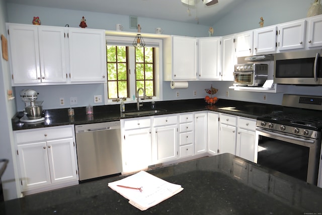 kitchen with appliances with stainless steel finishes, white cabinets, vaulted ceiling, sink, and ceiling fan