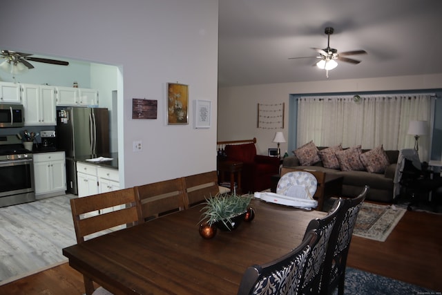 dining area with light hardwood / wood-style floors, ceiling fan, and vaulted ceiling