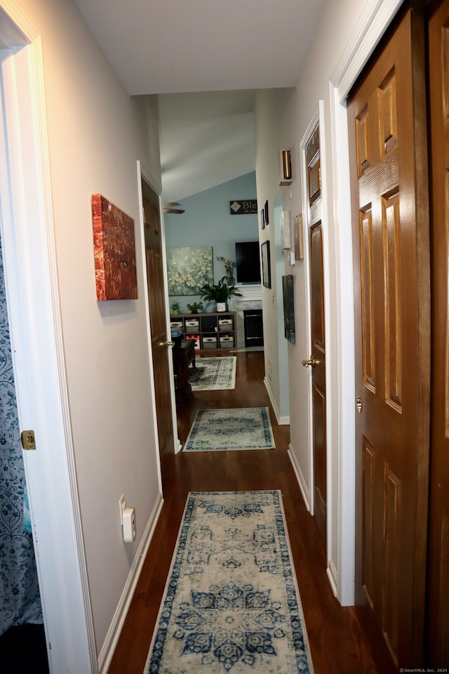 hall with vaulted ceiling and dark hardwood / wood-style flooring