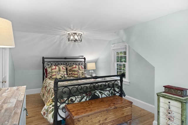 bedroom with vaulted ceiling and light wood-type flooring