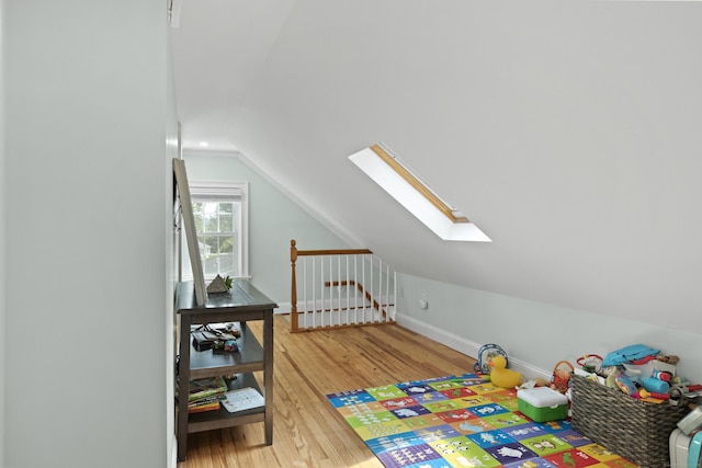 game room featuring hardwood / wood-style floors and lofted ceiling with skylight