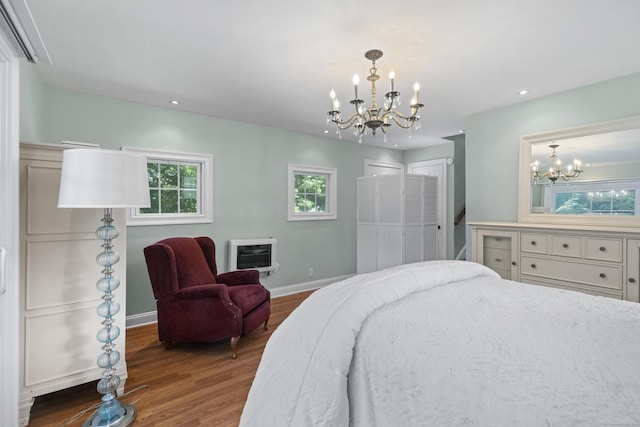 bedroom featuring heating unit, an inviting chandelier, a wall mounted air conditioner, dark hardwood / wood-style floors, and two closets