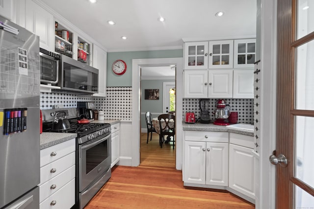 kitchen featuring white cabinetry, ornamental molding, appliances with stainless steel finishes, and decorative backsplash