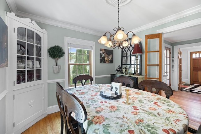 dining space with a notable chandelier, ornamental molding, and light hardwood / wood-style floors