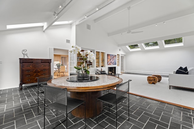 dining space featuring ceiling fan, baseboard heating, a skylight, track lighting, and beamed ceiling