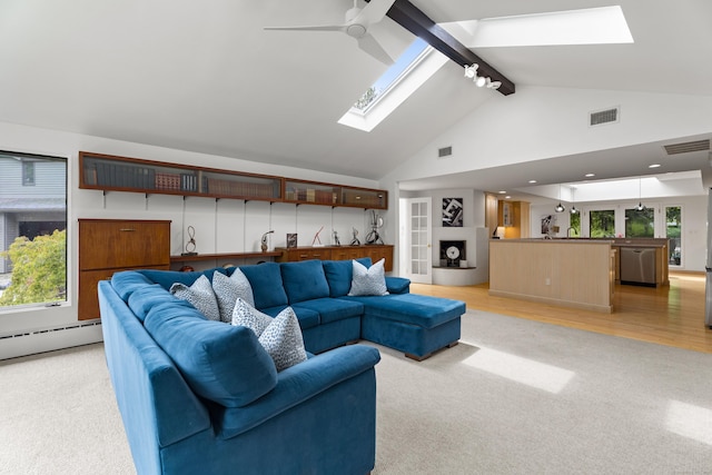 carpeted living room featuring high vaulted ceiling, a skylight, beamed ceiling, a baseboard heating unit, and ceiling fan