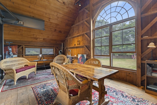 dining room featuring vaulted ceiling, light hardwood / wood-style flooring, wooden ceiling, and wood walls