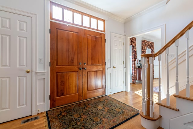 foyer entrance with light wood-type flooring and ornamental molding