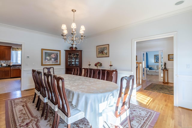 dining room with a chandelier, light hardwood / wood-style floors, and ornamental molding