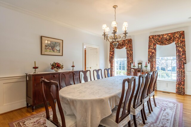 dining room with light hardwood / wood-style flooring, ornamental molding, and a notable chandelier