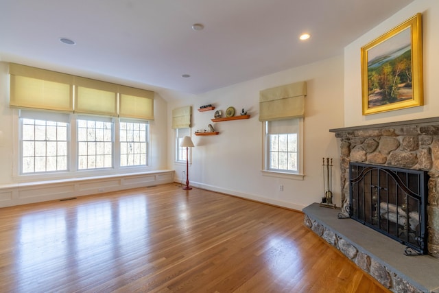 living room featuring hardwood / wood-style floors, a stone fireplace, and a wealth of natural light