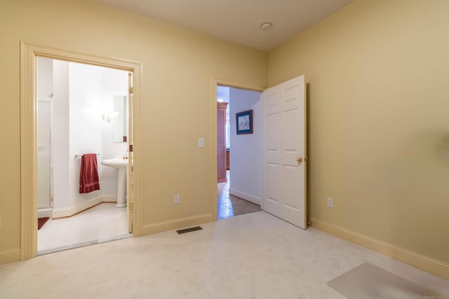 unfurnished bedroom featuring light carpet, connected bathroom, and sink