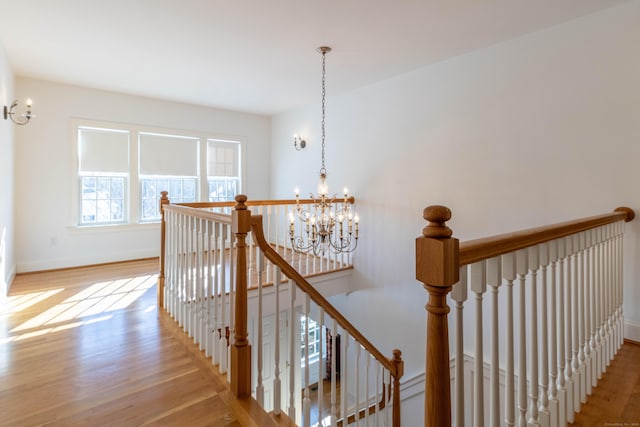 stairway with an inviting chandelier and hardwood / wood-style flooring