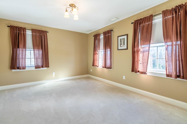 carpeted spare room featuring a chandelier