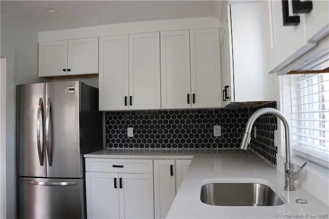 kitchen with white cabinets, sink, stainless steel refrigerator, and tasteful backsplash