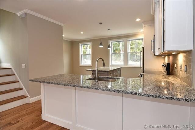 kitchen featuring light stone countertops, ornamental molding, stove, white cabinets, and a sink