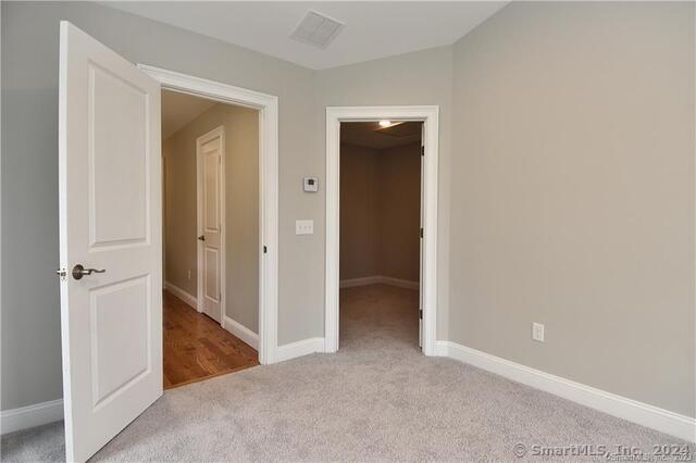 unfurnished bedroom with carpet, baseboards, and visible vents