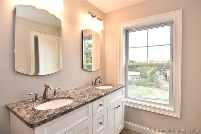 bathroom featuring double vanity, baseboards, and a sink