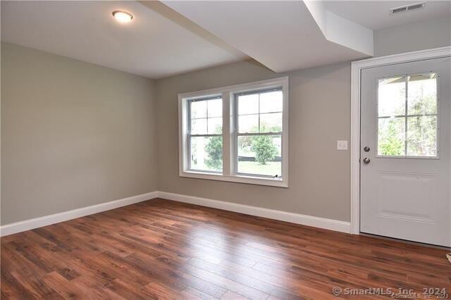 interior space with a wealth of natural light, baseboards, visible vents, and dark wood-style flooring