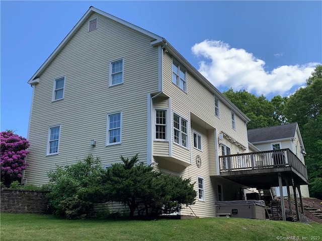 back of house with a deck and a lawn